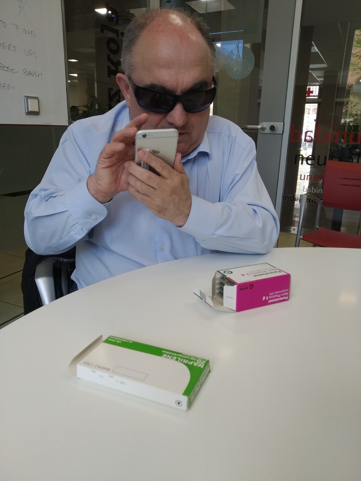 Andrés con la aplicación en el móvil y dos cajas de medicamentos sobre la mesa