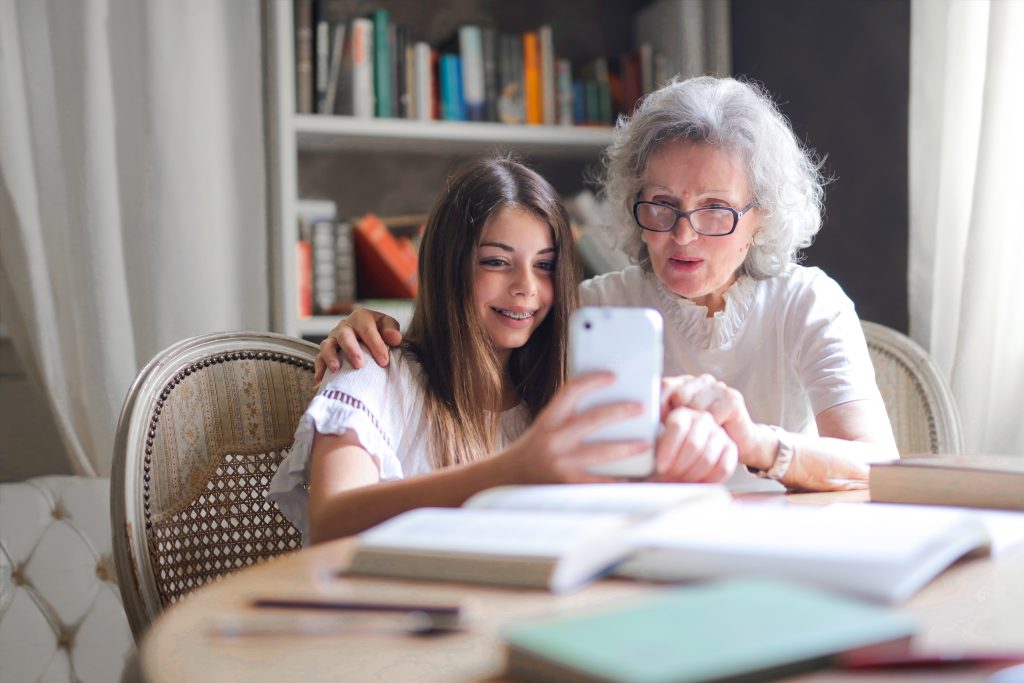 persona mayor usando el teléfono con su nieta