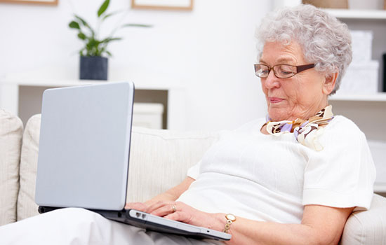 Image showing an elderly person using a laptop sitting on a sofa