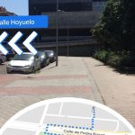 Captura de pantalla realidad aumentada de Google Maps. Se visualiza el mapa estándar en la parte inferior y en la parte superior señales de navegación sobre la imagen de la calle Hoyuelo.